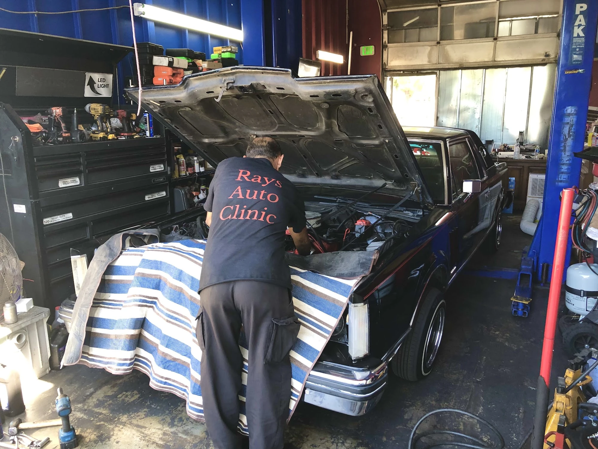 Ray in his Ray's Auto Clinic shirt working under the hood of a classic Lincoln